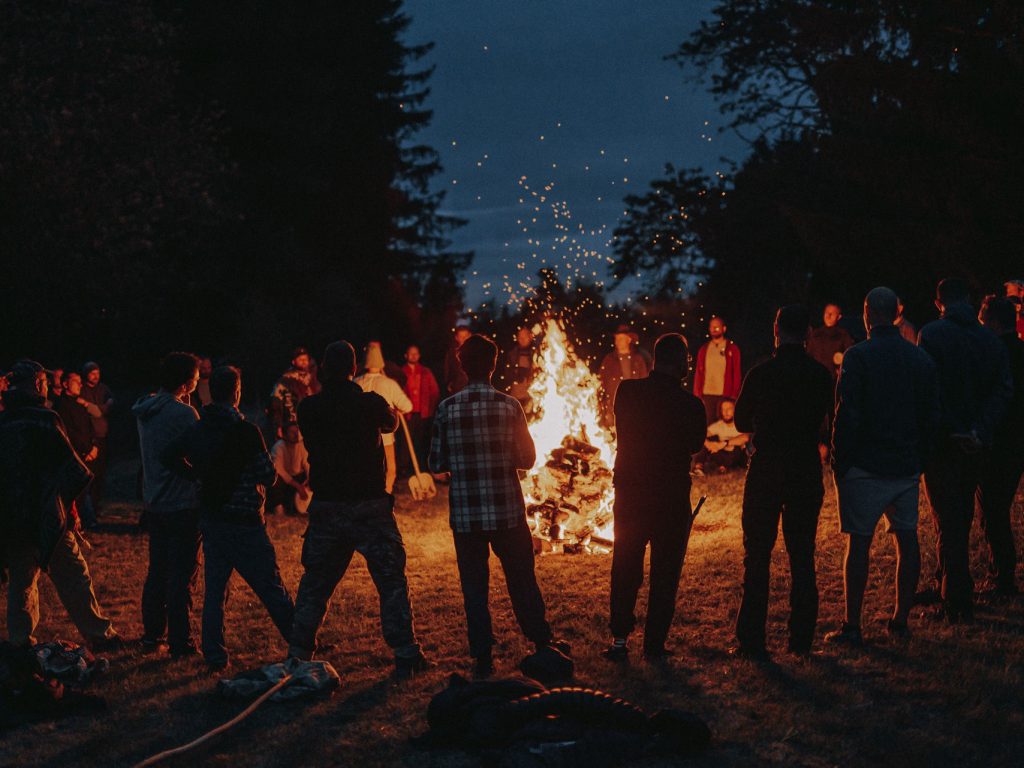 Muži pri spoločnom ohni v lese za súmraku